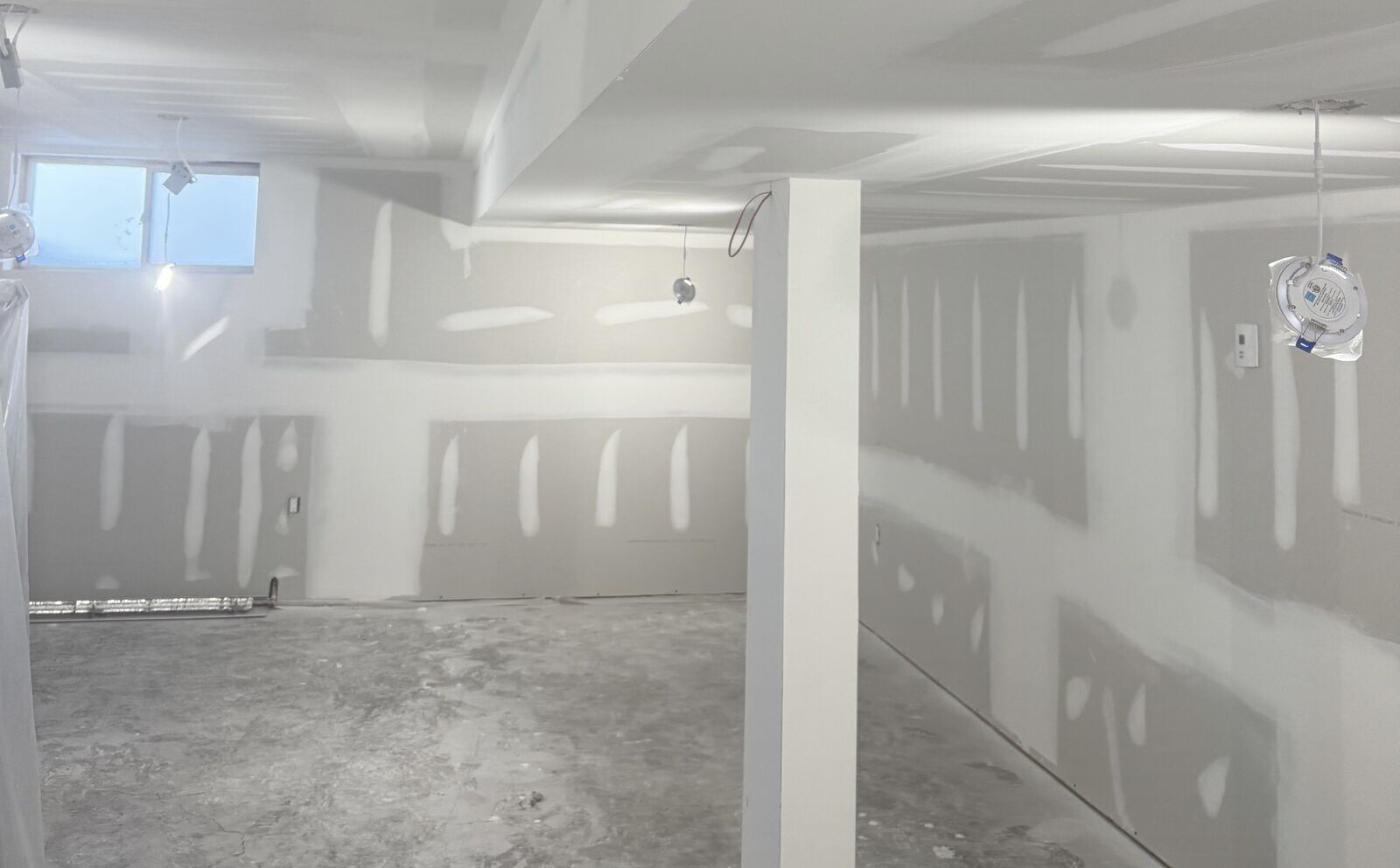 Basement renovation with drywall taped and coated, walls and column ready for sanding